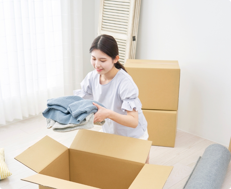 箱に服を詰める女性